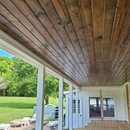 Covered porch with a natural wood ceiling and white framing